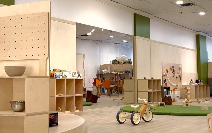 The Boogles Playhouse party room at Hillcrest Mall — birch play structures, a green play mat, and a mirror feature wall